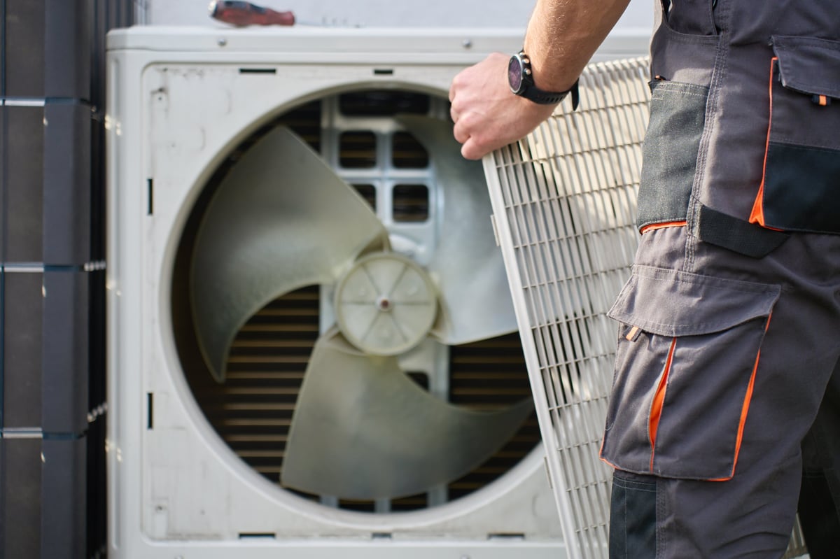 Technician testing an outdoor heat pump unit on a residential property